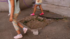 Niñas jugando en el patio alrededor del socavón dejado por una canasta caída y nunca repuesta.
