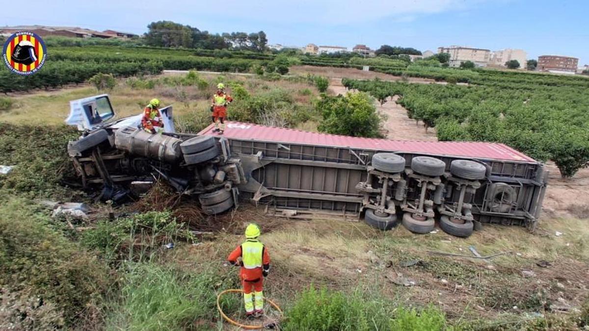 Efectivos del parque de bomberos de Alzira, con el camión accidentado.
