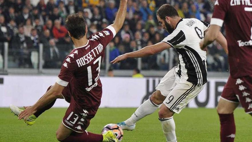 Higuaín, del Juventus, dispara ante la oposición de Rossettino, del Torino. // Giorgio Perotino