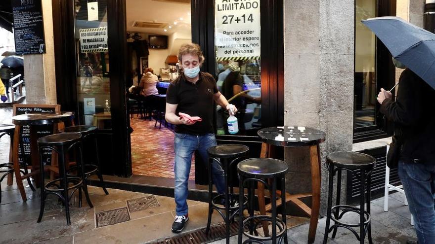 Un camarero se dispone a desinfectar el mobiliario del bar.