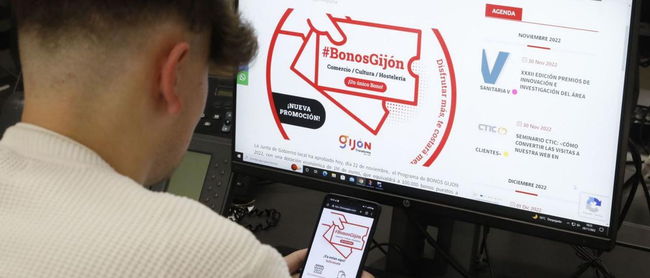 Un joven consulta la información sobre los bonos para potenciar el consumo en la web de Gijón Impulsa.