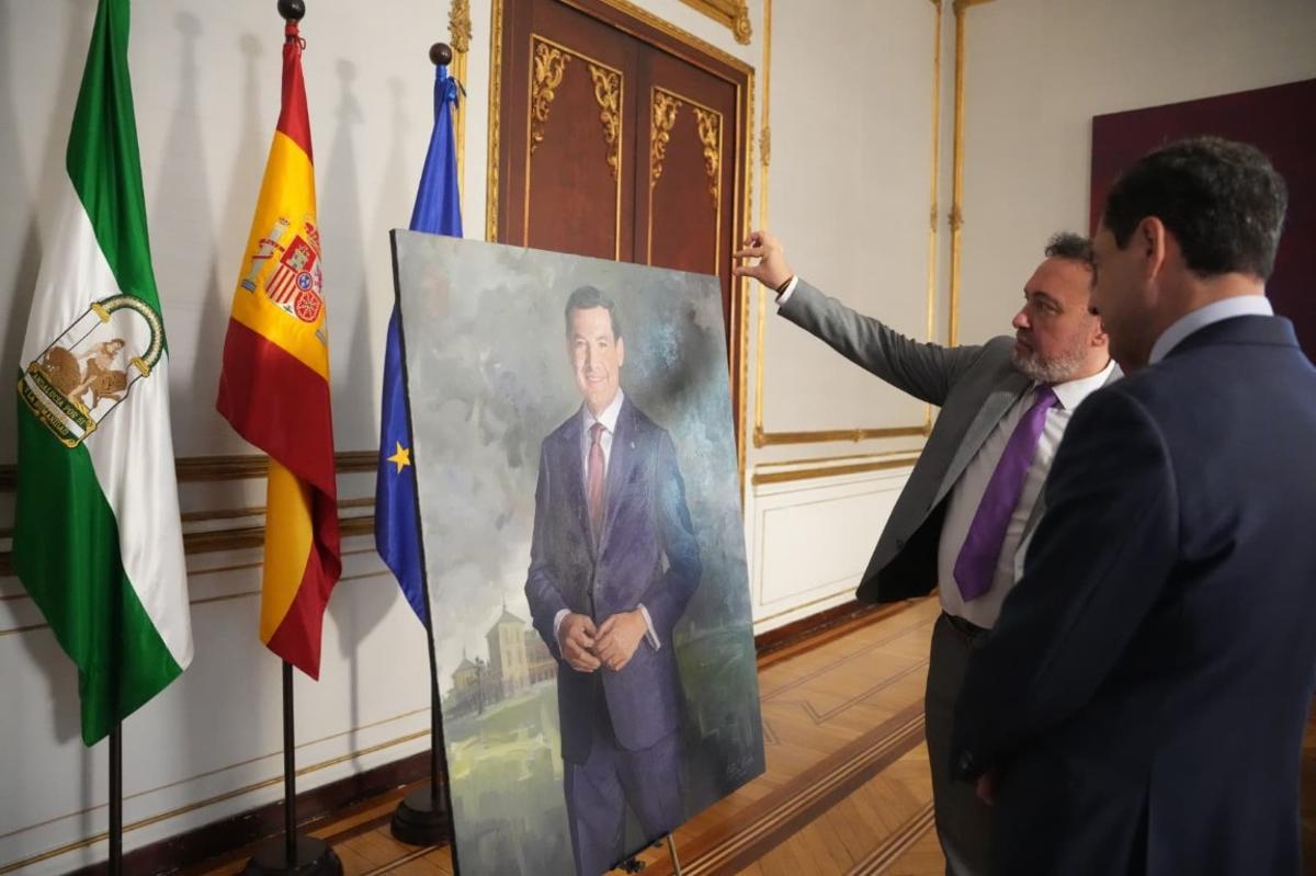 El pintor Cristóbal Córdoba muestra el retrato a Juanma Moreno en el Palacio de San Telmo de Sevilla.