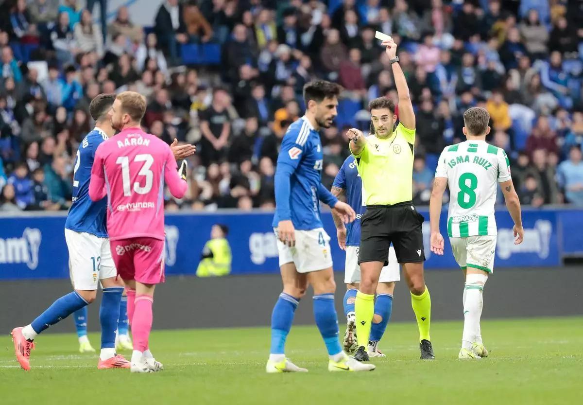 Mallo Fernández muestra una cartulina amarilla a un jugador local en el Oviedo-Córdoba CF de 2024.