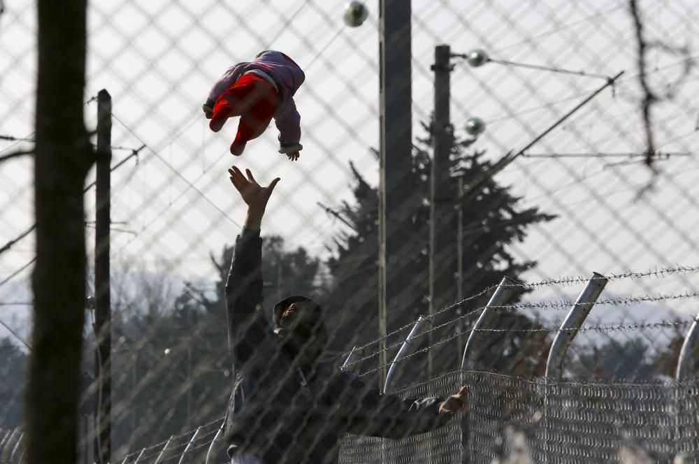 A migrant plays with his baby as they wait to ...