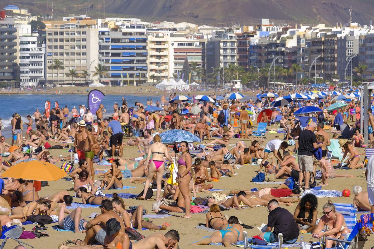 Turistas y residentes disfrutando de un día soleado en La Canteras.