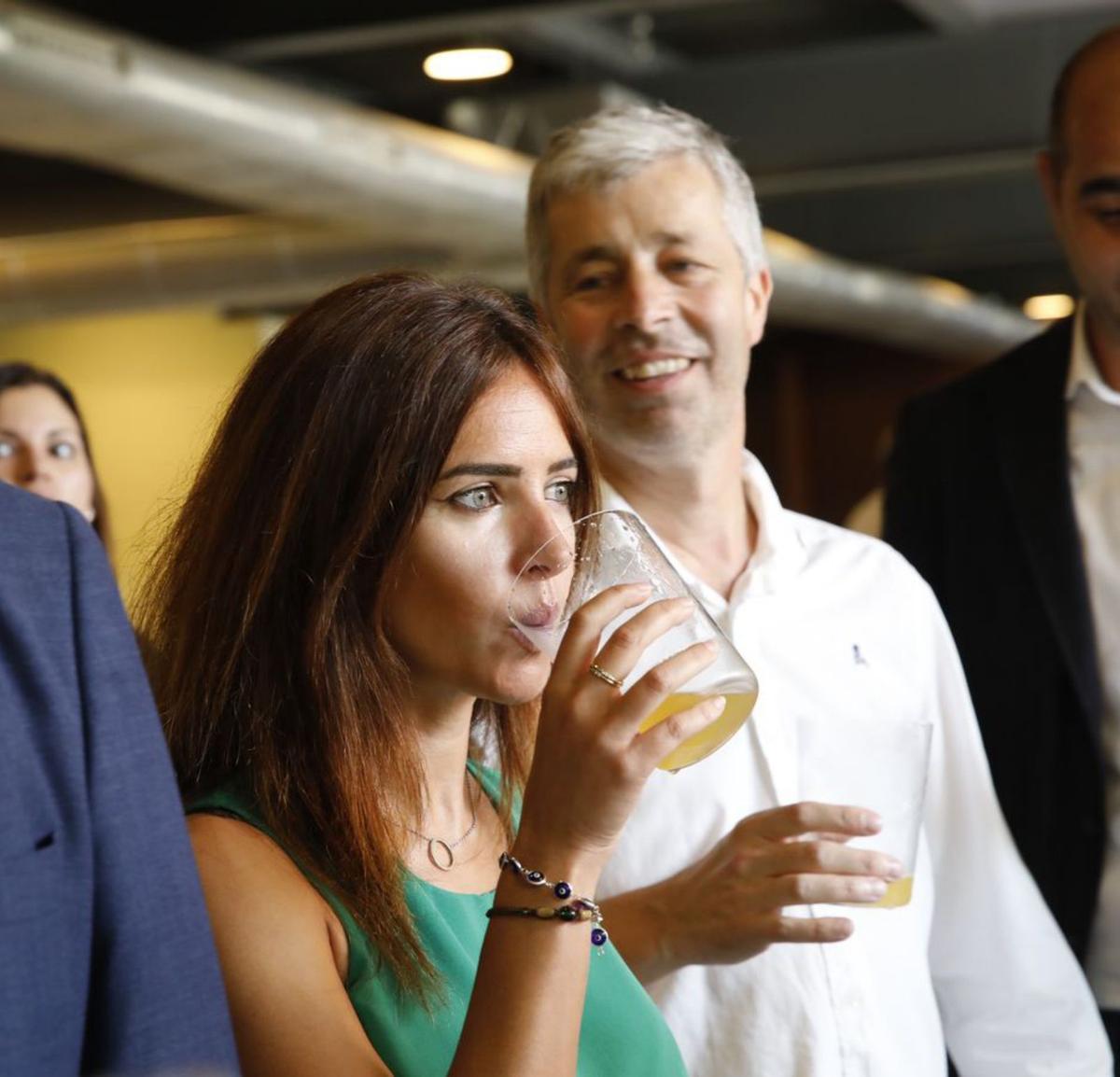 Paula Prendes sale de un tonel de sidra; abajo, tomando un culín de sidra Quelo, con Alberto Fanjul detrás, propietario del llagar ganador a la mejor sidra natural tradicional. | Á. G.