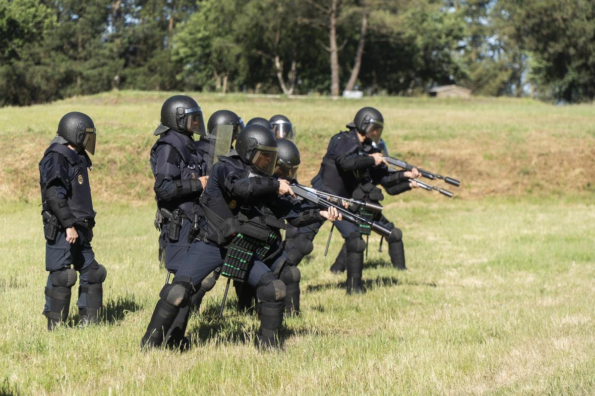 Policías con escopetas salen de detrás de los escudos de sus compañeros para hacer fuego.