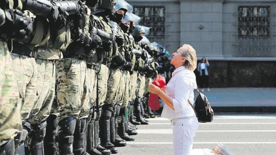 Una mujer arrodillada ante los antidisturbios en laprotesta de ayer en Minsk.