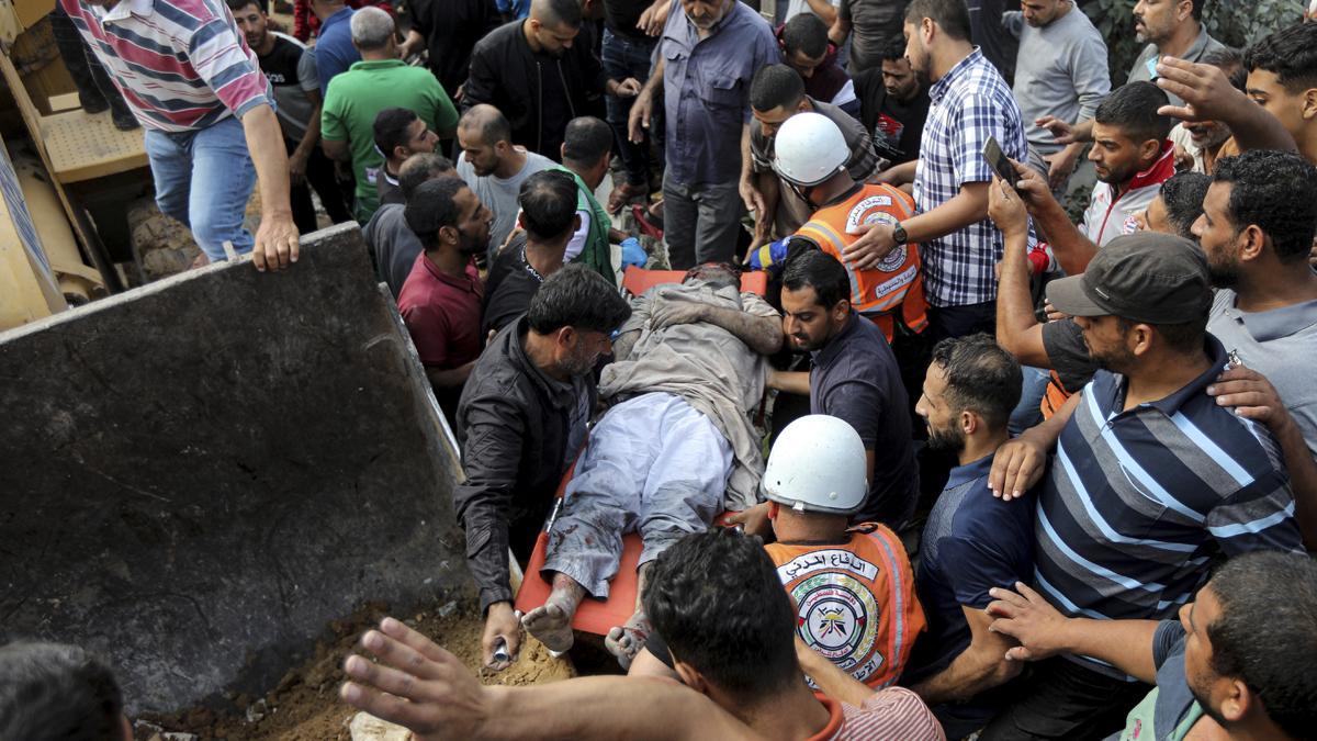 Ciudadanos palestinos llevan el cadáver de un hombre tras sacarlo de entre los escombros de un edificio residencial destruido por un ataque aéreo de Israel en Khan Younis, en la Franja de Gaza.