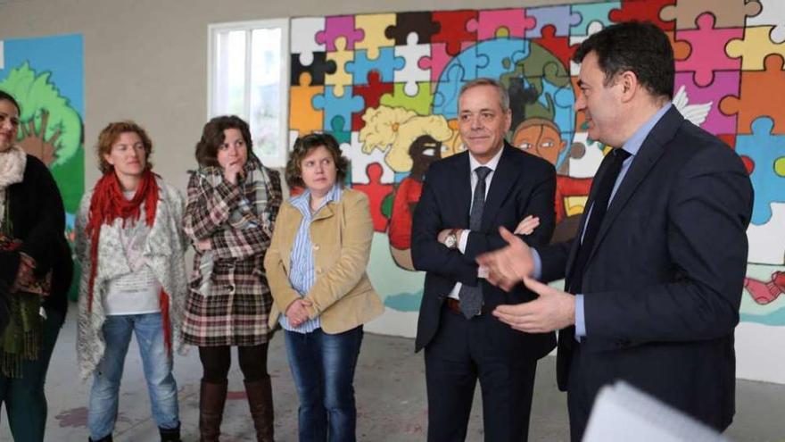 El conselleiro se dirige a madres de alumnos, junto al alcalde y con el nuevo mural del colegio como fondo. // Bernabé