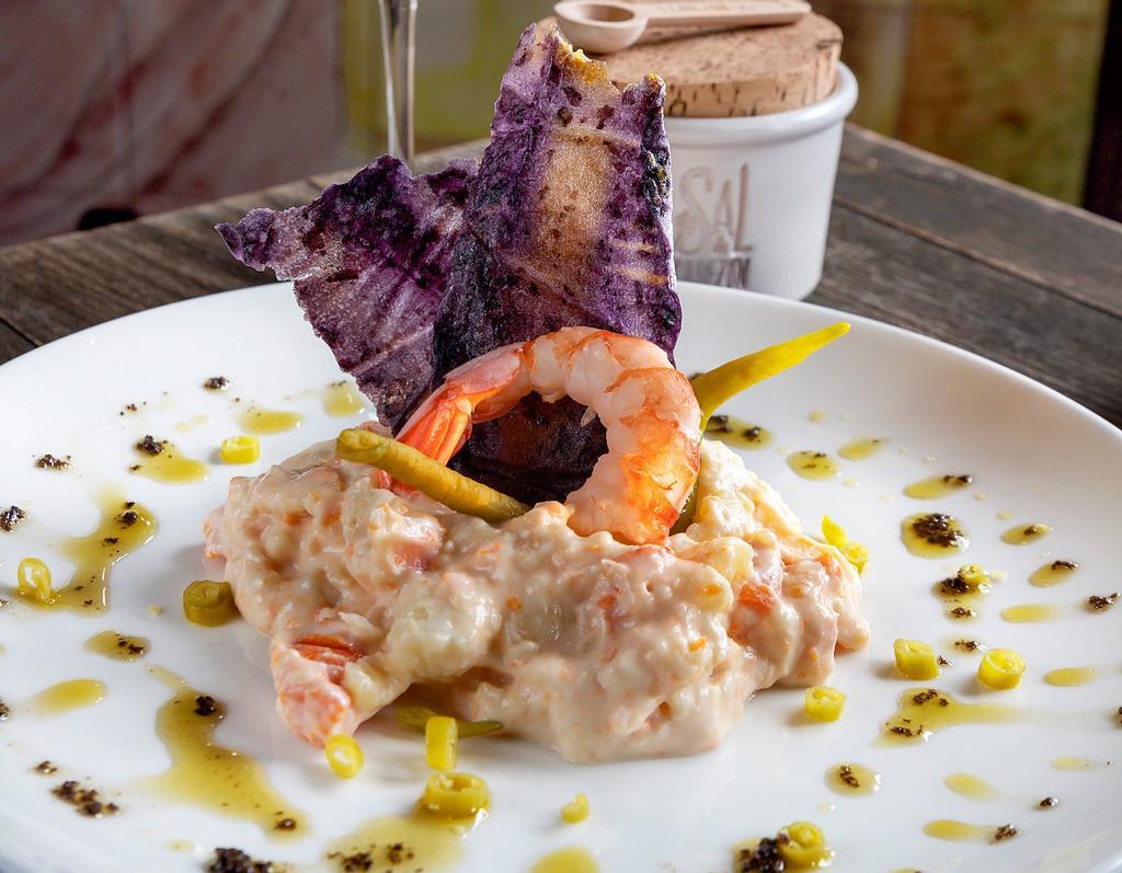 Ensaladilla de gambas: como todas las ensaladillas, lleva patata, zanahoria, huevo, mahonesa y gambas. Emplatar y adornar con un gambón, un crujiente de verduras y piparras y aliñar con aceite de oliva y aceitunas negras machacadas.