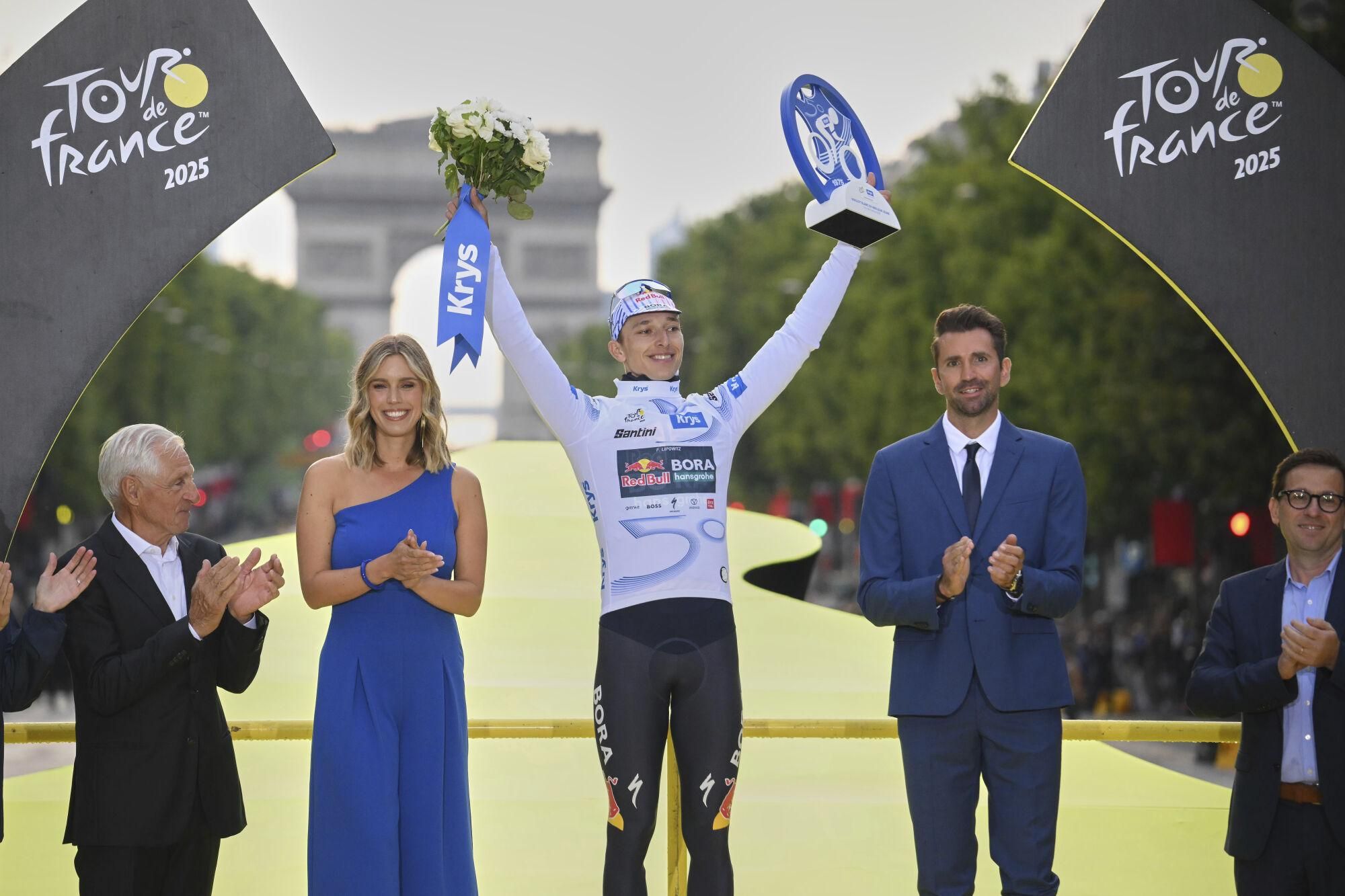 Germany's Florian Lipowitz stands on the podium holding the award for the best young rider, during the presentation ceremony for the Tour de France on the Champs-Elysees in Paris, France, Sunday, July 27, 2025. (Bernard Papon, Pool Photo via AP). POOL PHOTO