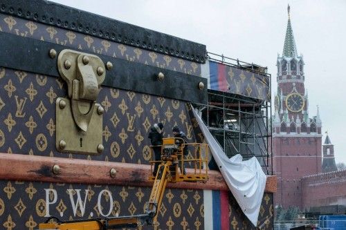 Workers disassemble a Louis Vuitton pavilion shaped like a giant suitcase as Kremlim's Spasskaya Tower is pictured behind in central Moscow