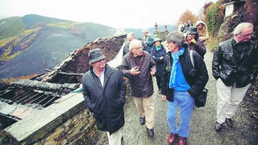 A la derecha, el grupo, ayer, de paseo por San Martín del Valledor; a la derecha, Antonio García Linares muestra los destrozos del fuego en la Torre del Valledor. | miki lópez
