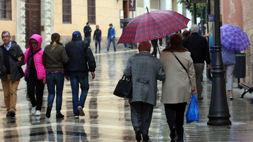 Varias personas pasean por el centro de Málaga en un día lluvioso.