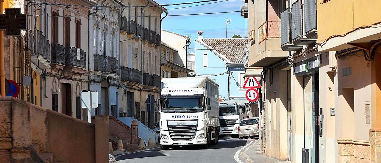 Un camión atraviesa el casco urbano de Pedralba, que tiene proyectada una ronda por el exterior. | PACO CALABUIG