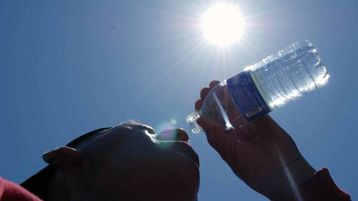 Un hombre bebe agua en una jornada de calor intenso.