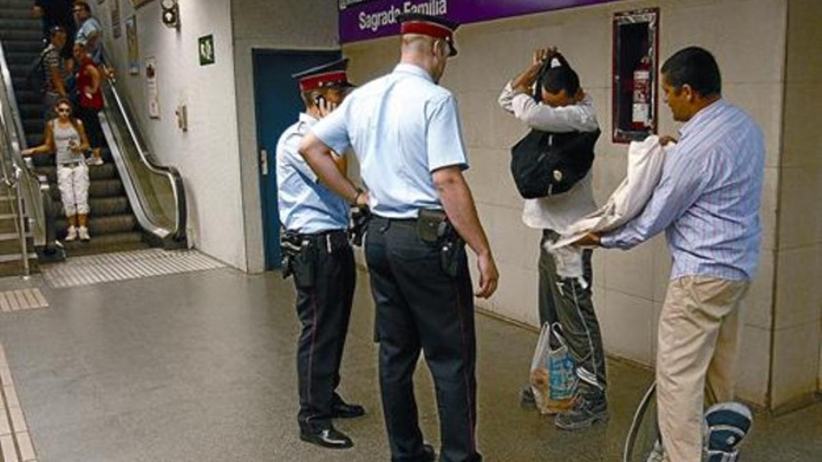 Una pareja de mossos identifica a unos sospechosos, el pasado 23 de julio, segundo día del dispositivo Xarxa, en el metro de Sagrada Família.