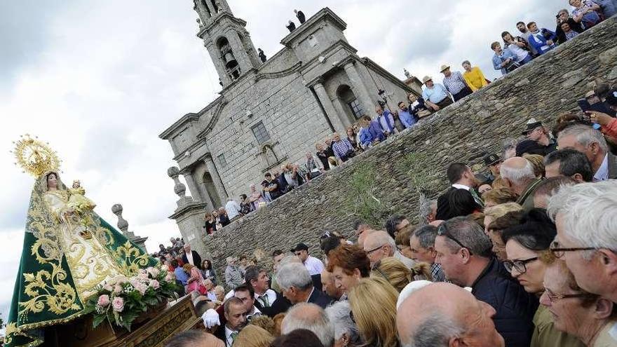 La imagen de la Virgen, en procesión entre los fieles, con el santuario al fondo. // Bernabé/Javier Lalín