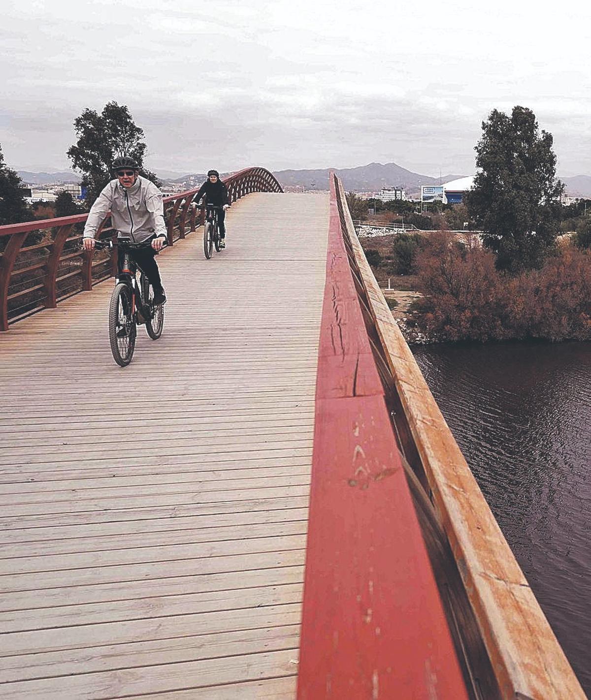 Ciclistas sobre la pasarela de madera del Guadalhorce.
