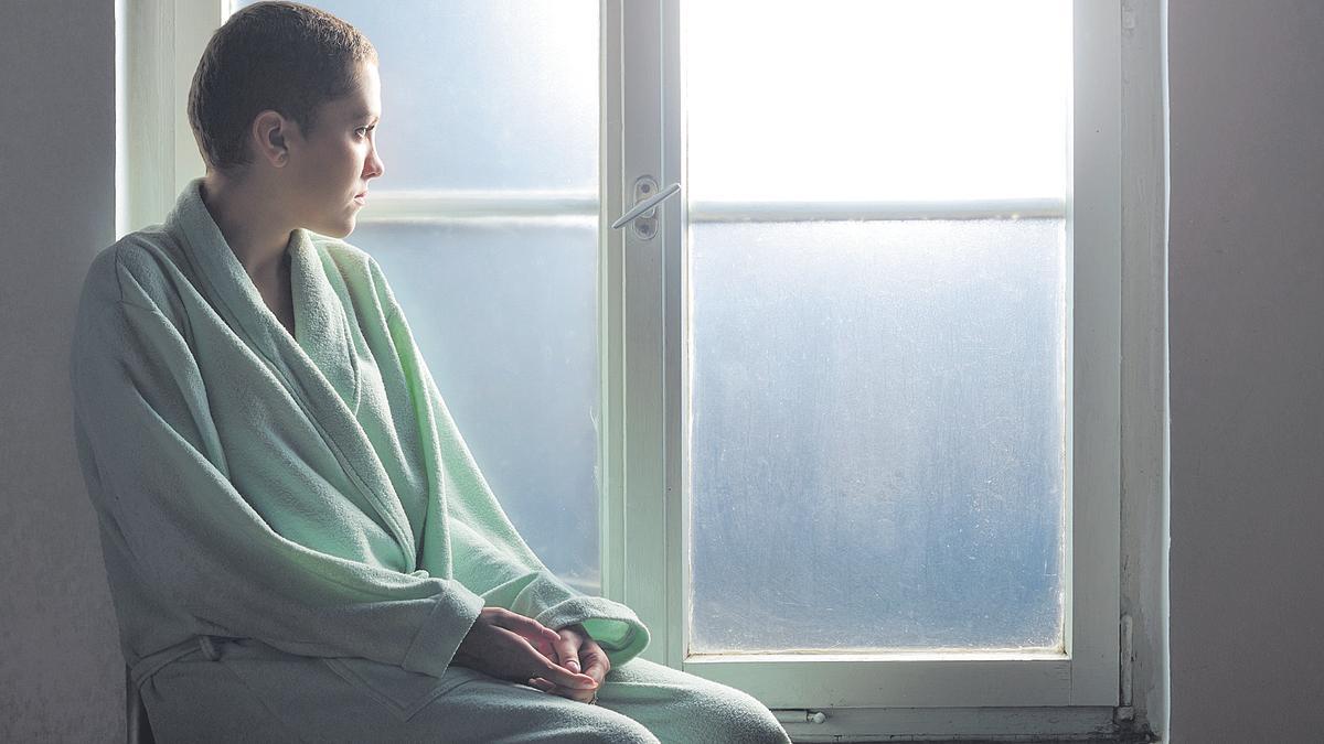 Paciente de cáncer sentada frente a la ventana del hospital.