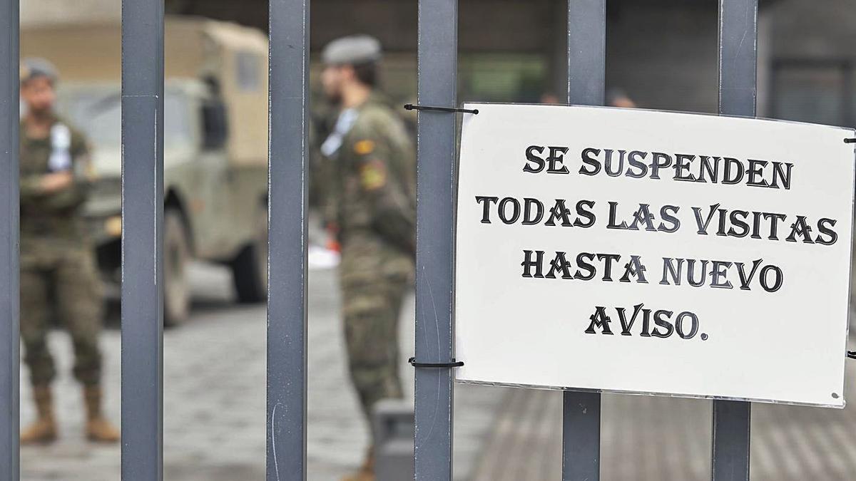 Un cartel de suspendidas las visitas en el geriátrico del Nodo con unos militares al fondo, durante la primera ola de la pandemia. | Mara Villamuza