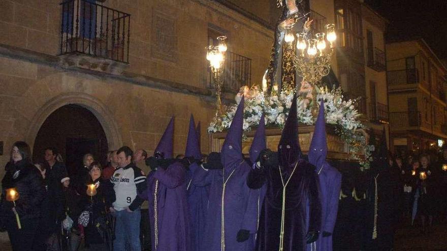 Cofrades portan a hombros la imagen titular de la cofradía por la calle El Sol en un desfile.