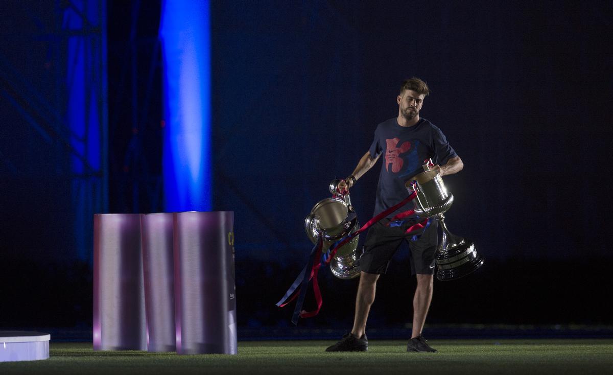 Piqué con los trofeos en la mano celebrando el triplete con la afición en el Camp Nou en junio de 2015.