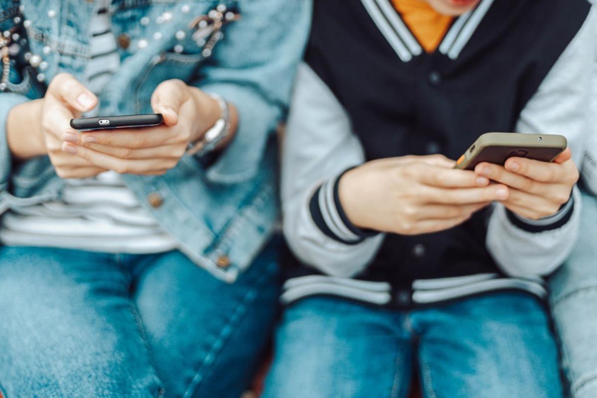 Dos adolescentes atentos a las pantallas de sus teléfonos móviles. Dos adolescentes atentos a las pantallas de sus teléfonos móviles.