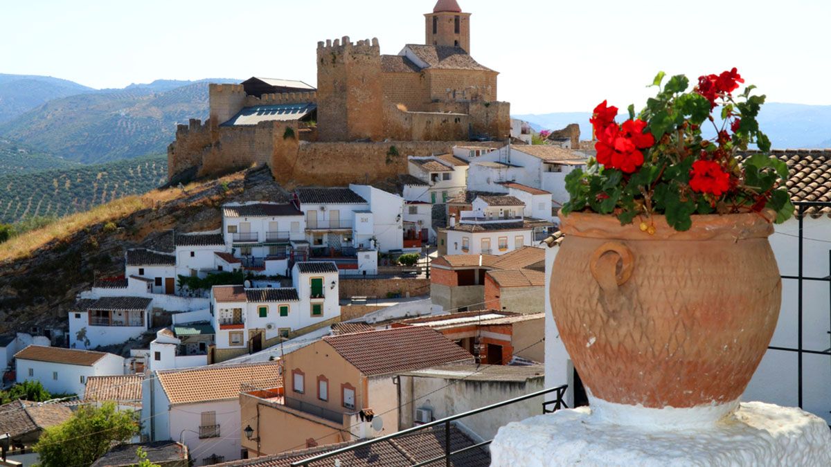 El imponente castillo medieval de Iznájar, acompañado por la iglesia parroquial, domina el caserío blanco que se extiende a sus pies entre colinas de olivos
