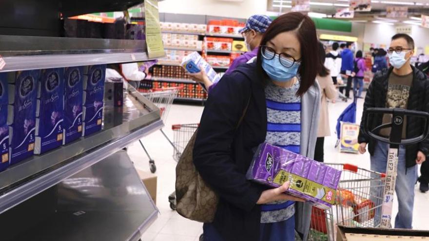 Una mujer mira el estante vacío en un supermercado local.