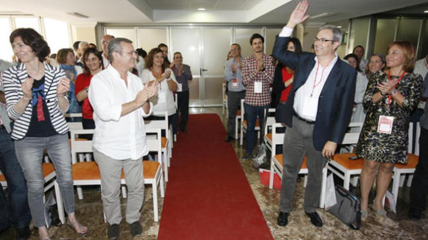 Vicent Torres, junto a su pareja, alza el brazo mientras recibe aplausos y, en la otra fila, el presidente de la gestora, Joan Boned.