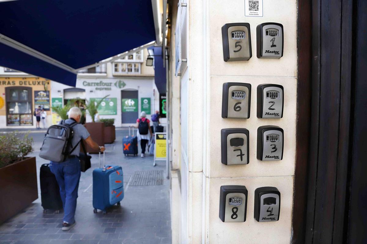 Varios turistas pasan cerca de cajas o cajetillas de llaves de los pisos turísticos que hay en el casco histórico de Málaga