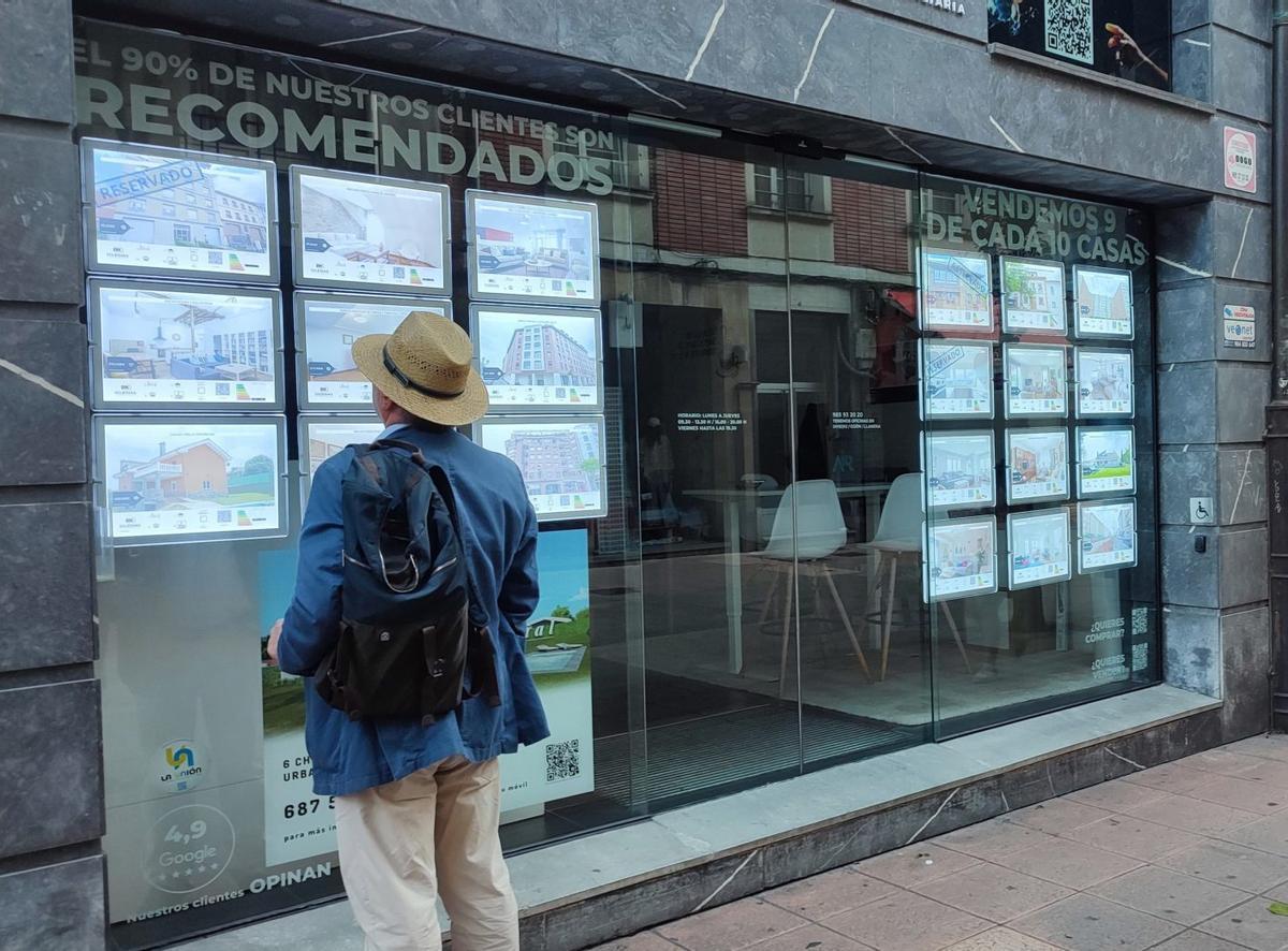 Un hombre mira el escaparate de una agencia inmobiliaria.
