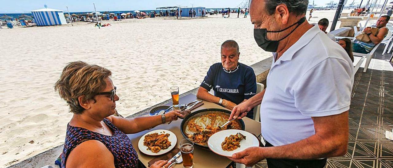 Un camarero atiende a los clientes en la playa de València.