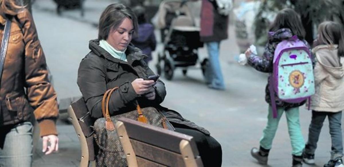 La Marina consulta el telèfon mòbil en un banc d’un carrer de Barcelona, ahir.