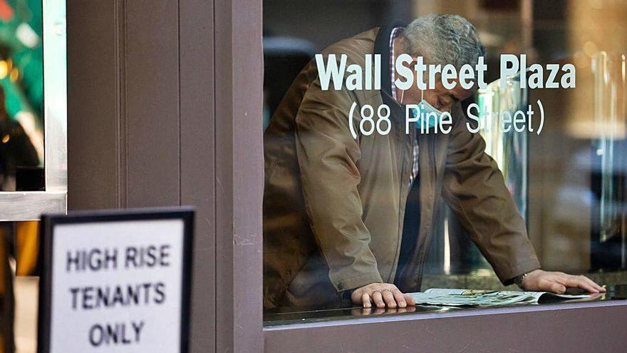 Un home amb una màscara llegeix un diari ahir, a Wall Street