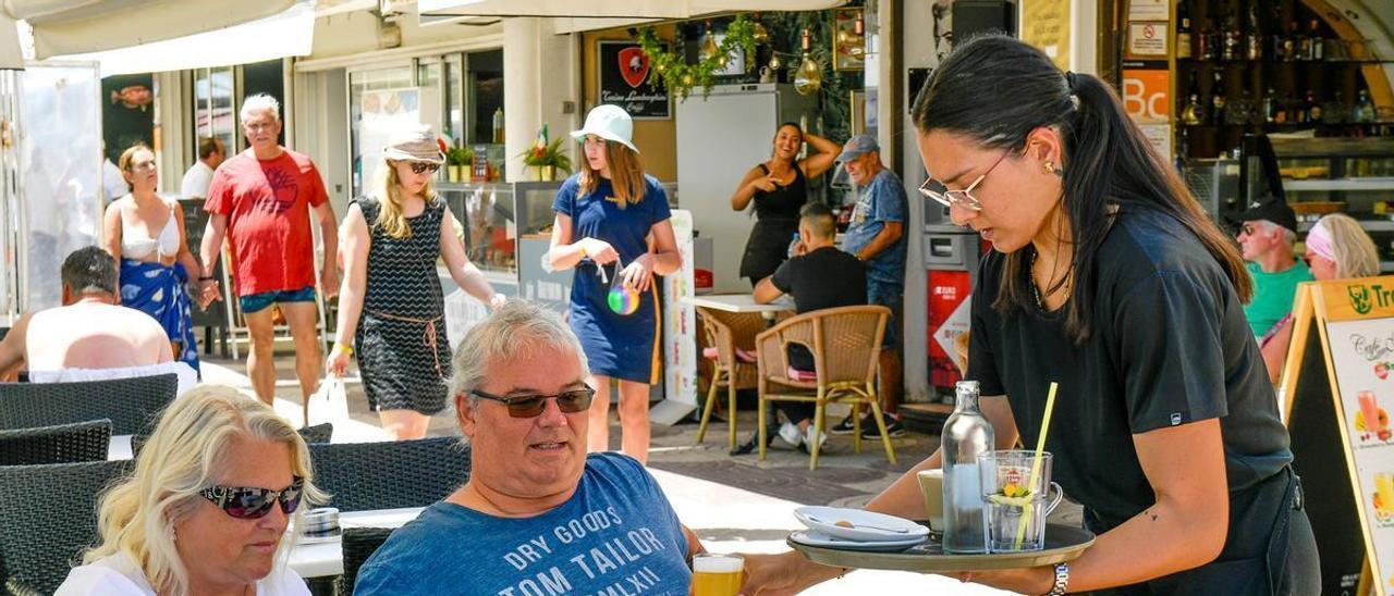 Una camarera de un establecimiento en el sur de Gran Canaria sirve una cerveza a un turista.