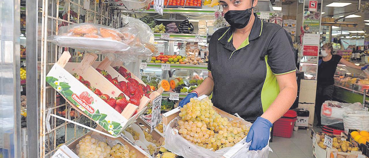 Judith Quintana, en la frutería familiar de la calle Venegas, coge una caja de uvas blancas en venta para la Nochevieja.