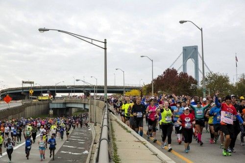 The Verrazano-Narrows Bridge is seen behind runners as they enter the borough of Brooklyn after the start of the New York City Marathon in New York