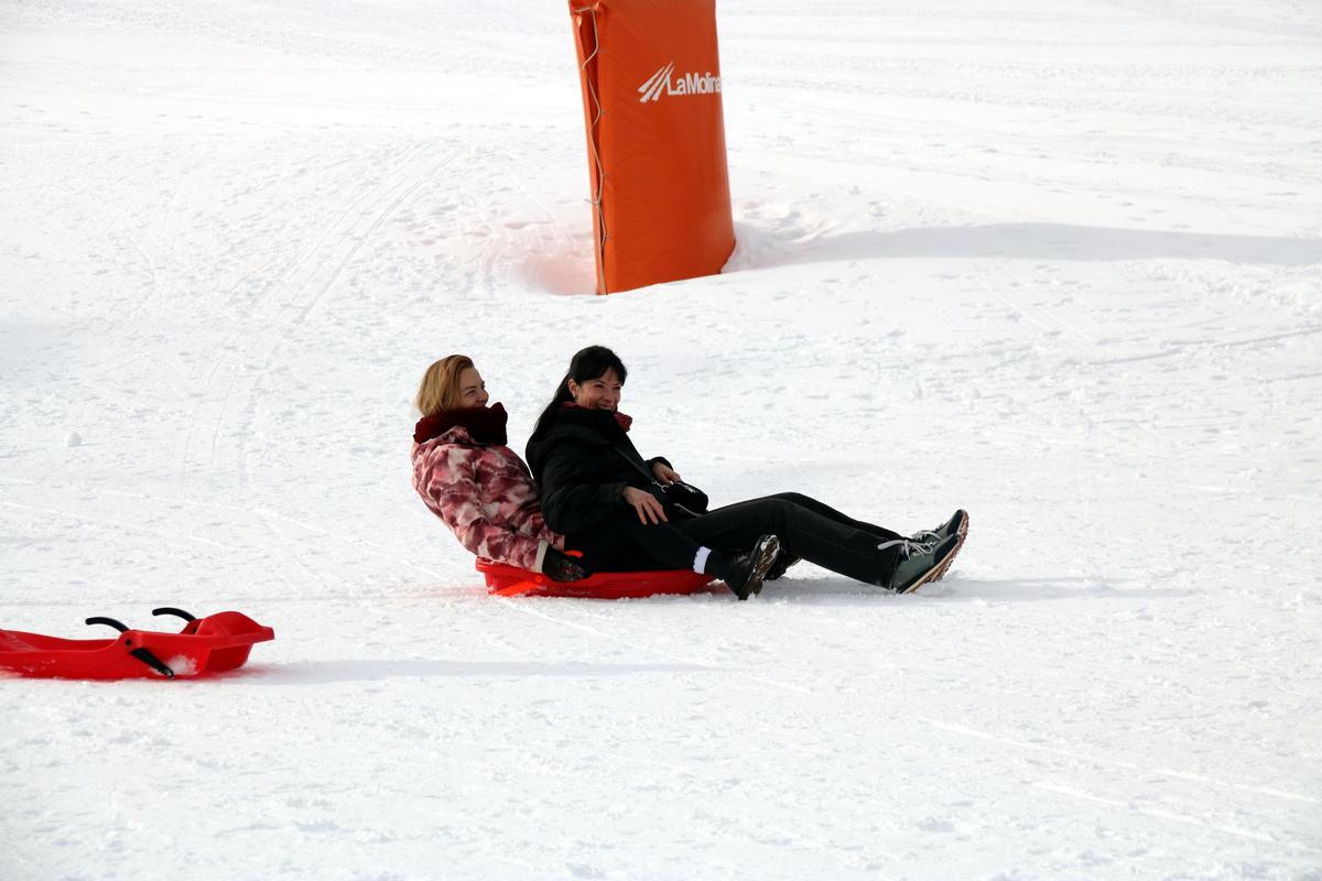 Dues dones baixant amb un trineu i rient