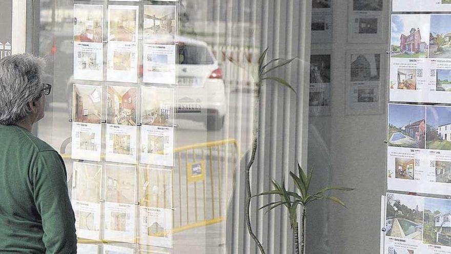 Un hombre observa los carteles de pisos en venta en una inmobiliaria de A Coruña. // Victor Echave