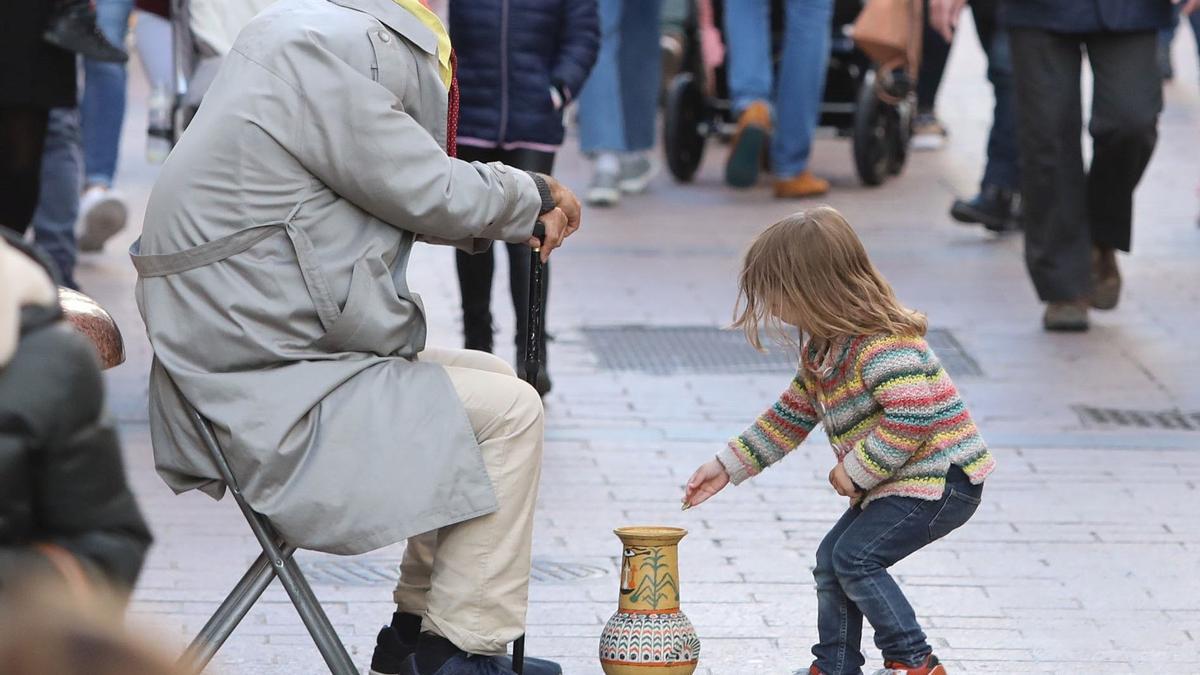 Una niña da unas monedas a una persona