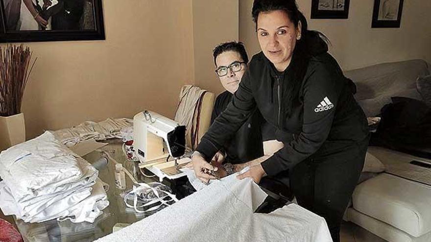 Miguel Ãngel y Olga, en su casa en plena confecciÃ³n de mascarillas.