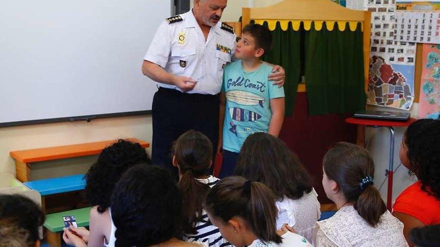 El comisario Manuel Bouzas hace entrega de uno de los carnés de &quot;ciberexperto&quot; a un niño. // G. S.