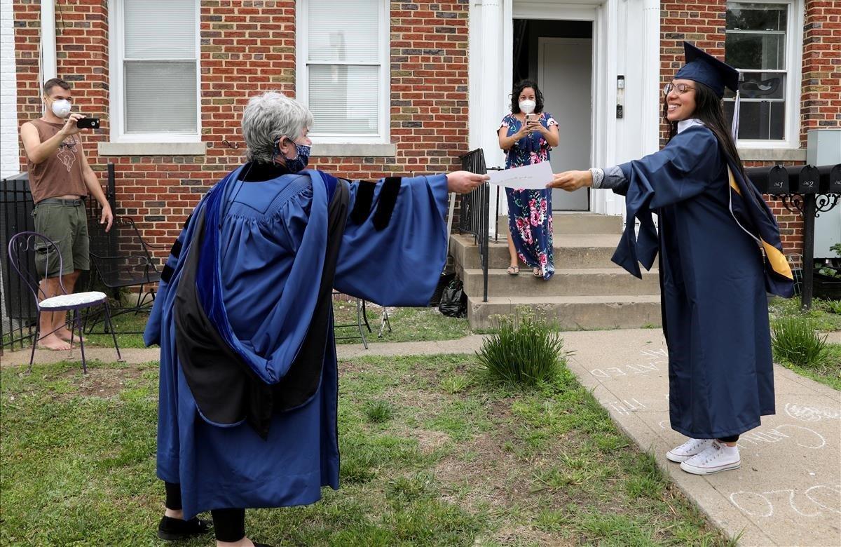 La graduada de la Universidad George Washington, Catalina Pérez, recibe una copia en papel de su diploma mientras mantiene La distancia social en una fiesta sorpresa de graduación.