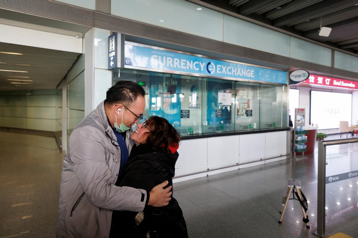 Una pareja se abraza en la puerta de llegadas internacionales del Aeropuerto Internacional Capital de Beijing después de que China levantara el requisito de cuarentena de la enfermedad por coronavirus.