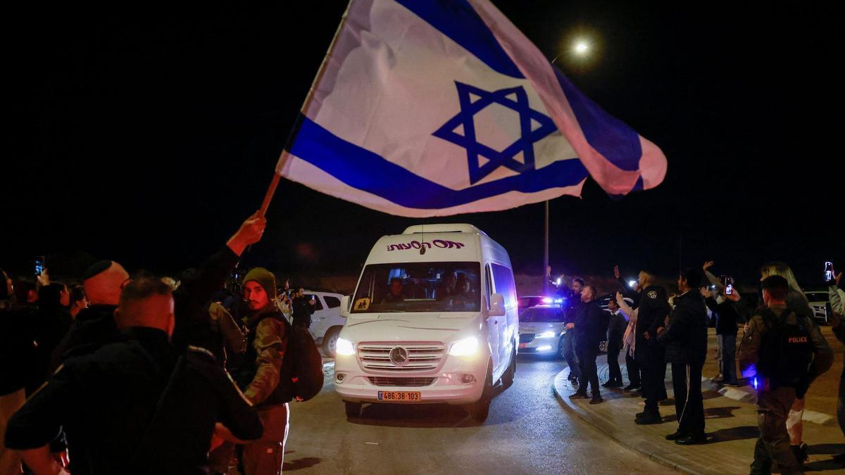 Un hombre ondea una bandera israelí al paso de la ambulancia que transportaba a los dos rehenes liberados este miércoles por Hamás.