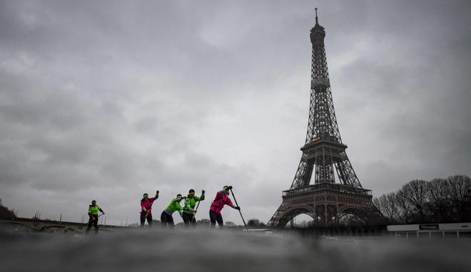 Los corredores de Stand Up Paddle pasan cerca de la Torre Eiffel en el río Sena en París.