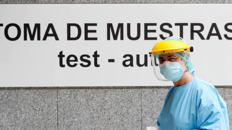 Un sanitario frente a un cartel de toma de muestras